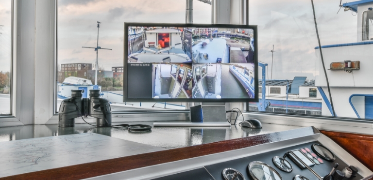 Kontrollraum mit mehreren Bildschirmen, auf denen verschiedene Hafenansichten zu Überwachungs- und Navigationszwecken angezeigt werden.