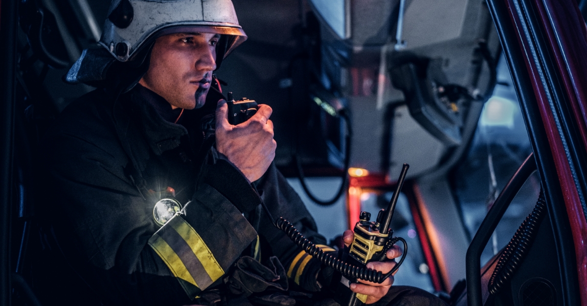 Firefighter communicating via radio in a vehicle, emphasizing mission-critical communication.